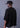 Person wearing a black oversized shirt and cap against a gray background