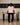 Person wearing black pants and pink top sitting on a table 