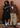 Two models posing in front of a wood-paneled wall. The model on the left wears a black cropped hoodie with 'WE ARE GO' printed in white across the chest, paired with a long black skirt.
